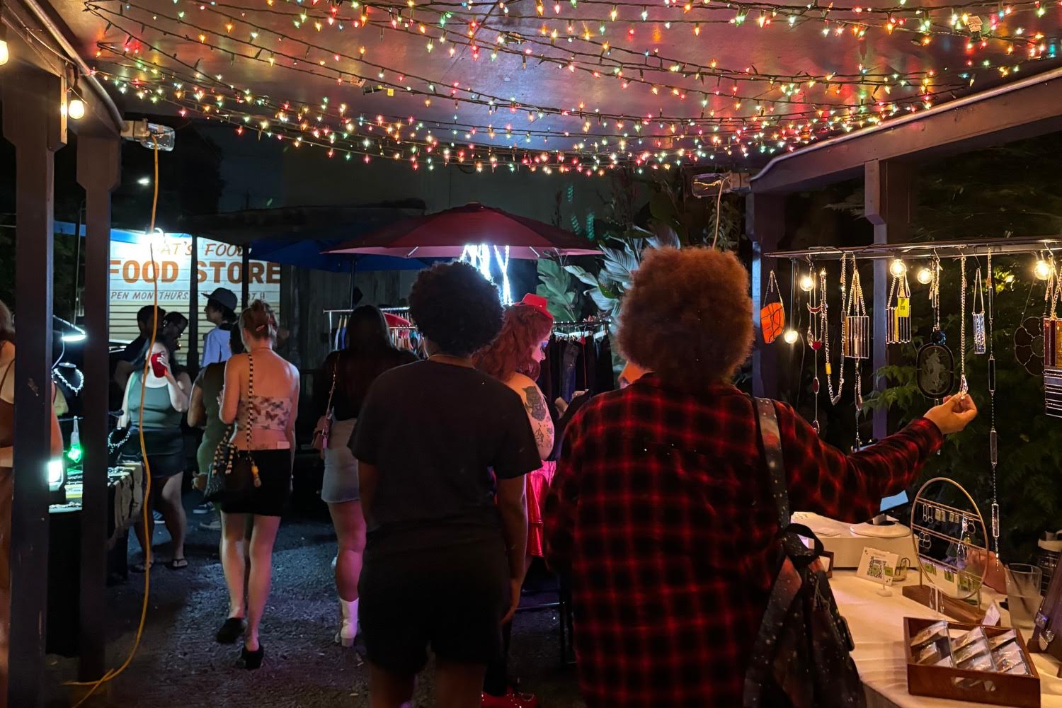 A diverse crowd shops from vendors on the patio of a cool bar